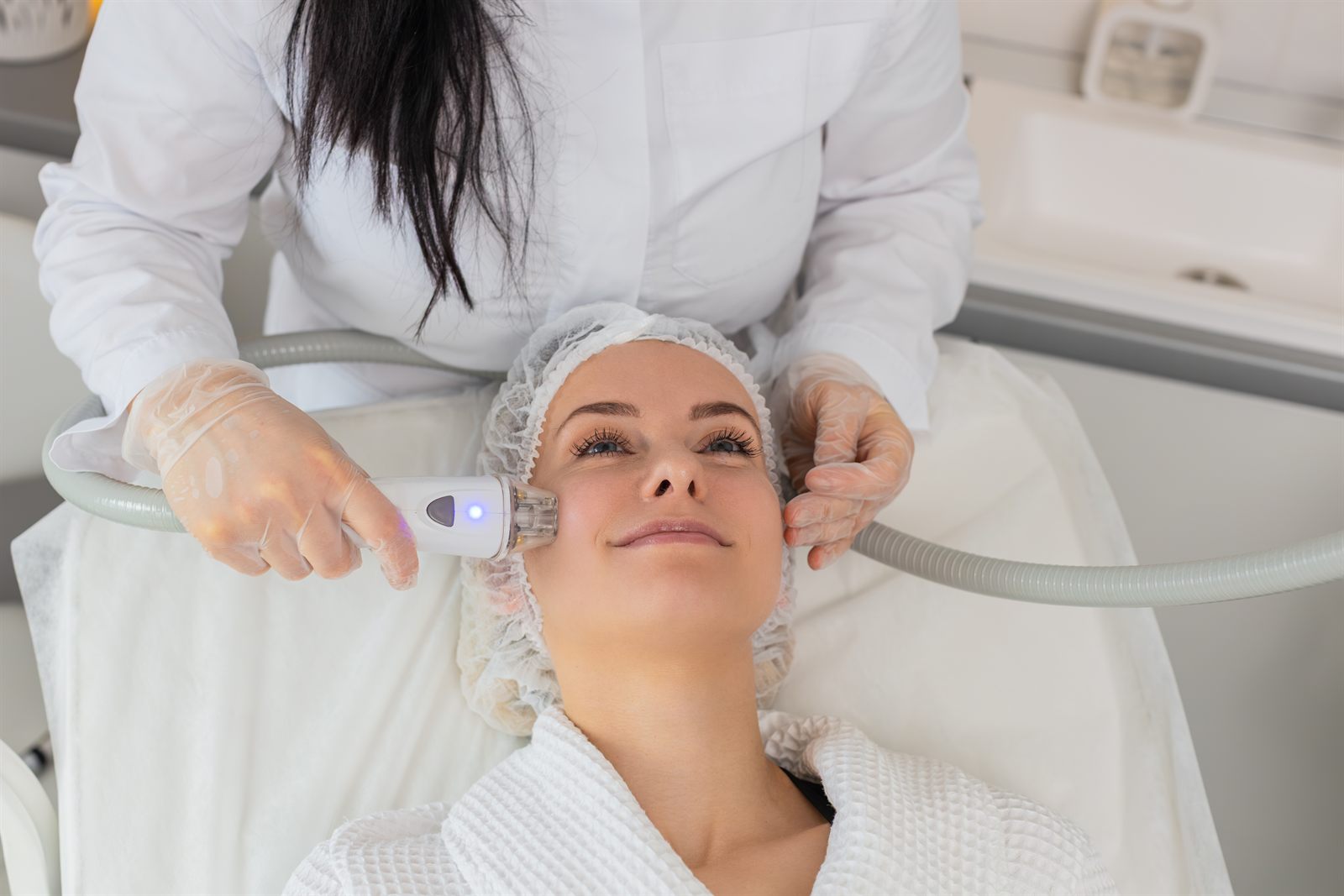 Paciente recebendo sessão de tratamento facial com equipamento em clínica de estética