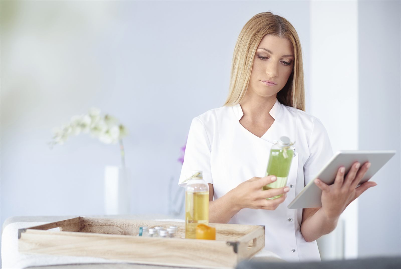 Profissional de estética consultando um tablet no ambiente da clínica